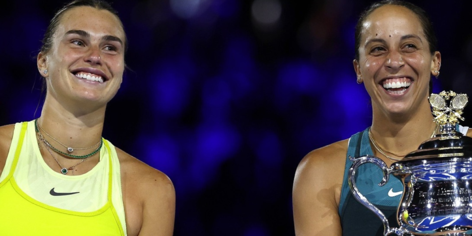 Aryna Sabalenka, wearing a bright yellow top, and Madison Keys, in a teal outfit, smiling together as Madison holds the trophy after her singles victory at the Australian Open 2025