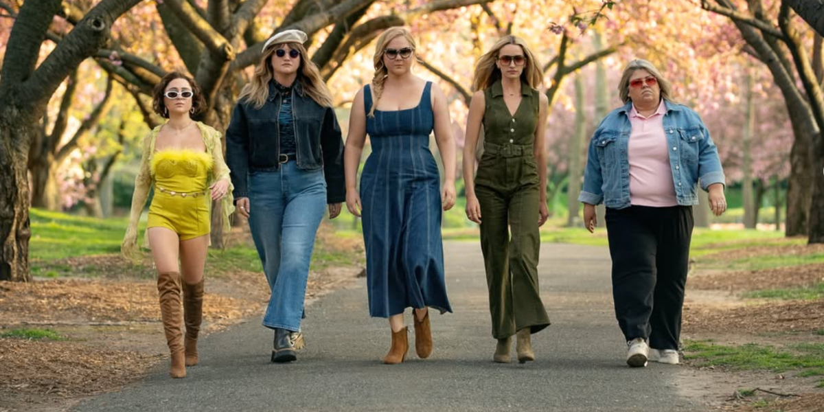 Lizze Broadway as Shirley, Jillian Bell as Kate, Amy Schumer as Lainy, Brianne Howey as Megan, and Urzila Carlson as Fallon walking together in a park, a scene from Kinda Pregnant (2025)