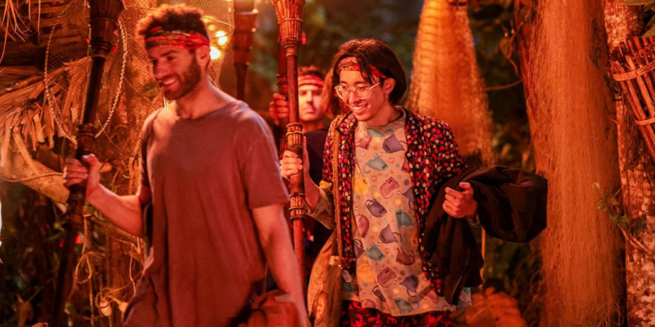 AJ and Myles from Australian Survivor 2025 walking away from Tribal Council at night, both smiling while holding their torches