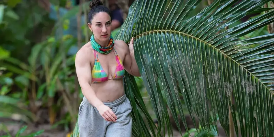 Ursula from Australian Survivor 2025 carries a large palm leaf through the jungle